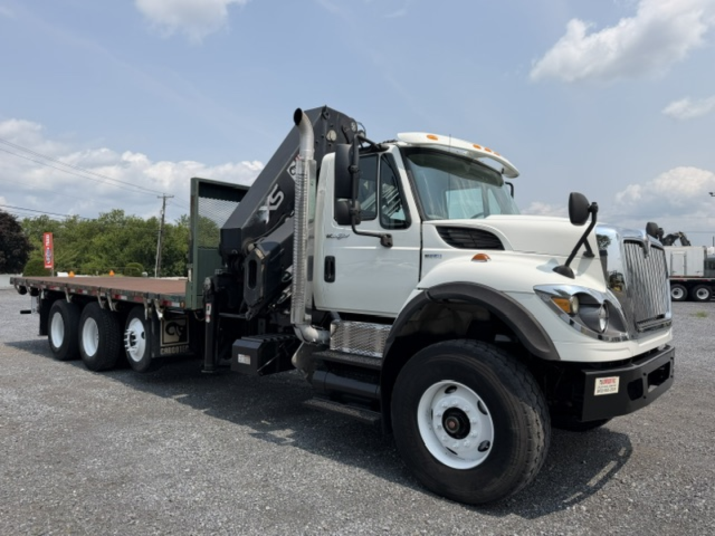 International 7600 SBA Work Star truck with crane on a gravel lot, white cab, flatbed with black crane arm, front grille, and dual rear axles.