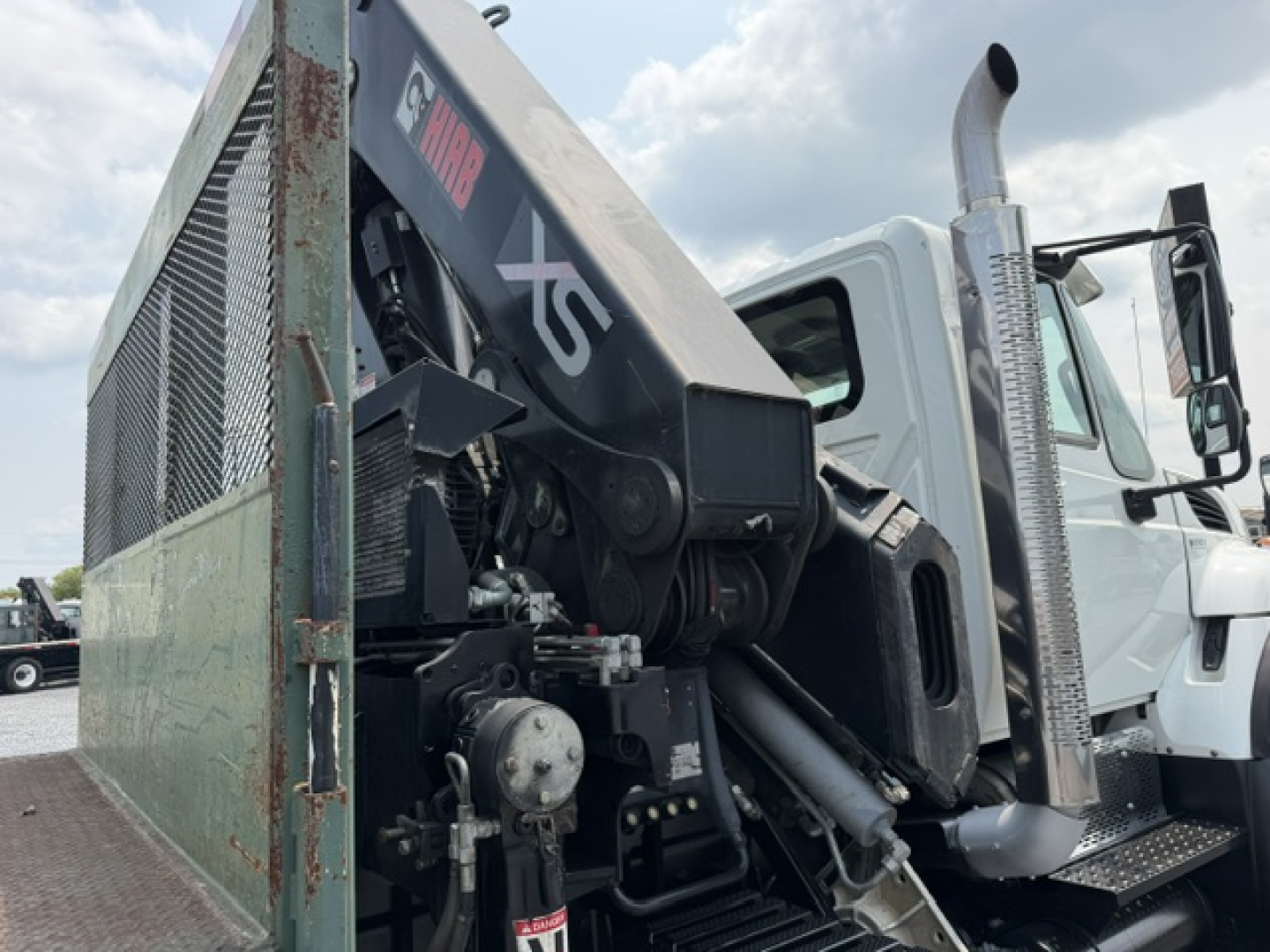 International 7600 SBA Work Star truck with crane attachment in side view showing hydraulic joints, black crane arm, and metal mesh cage.