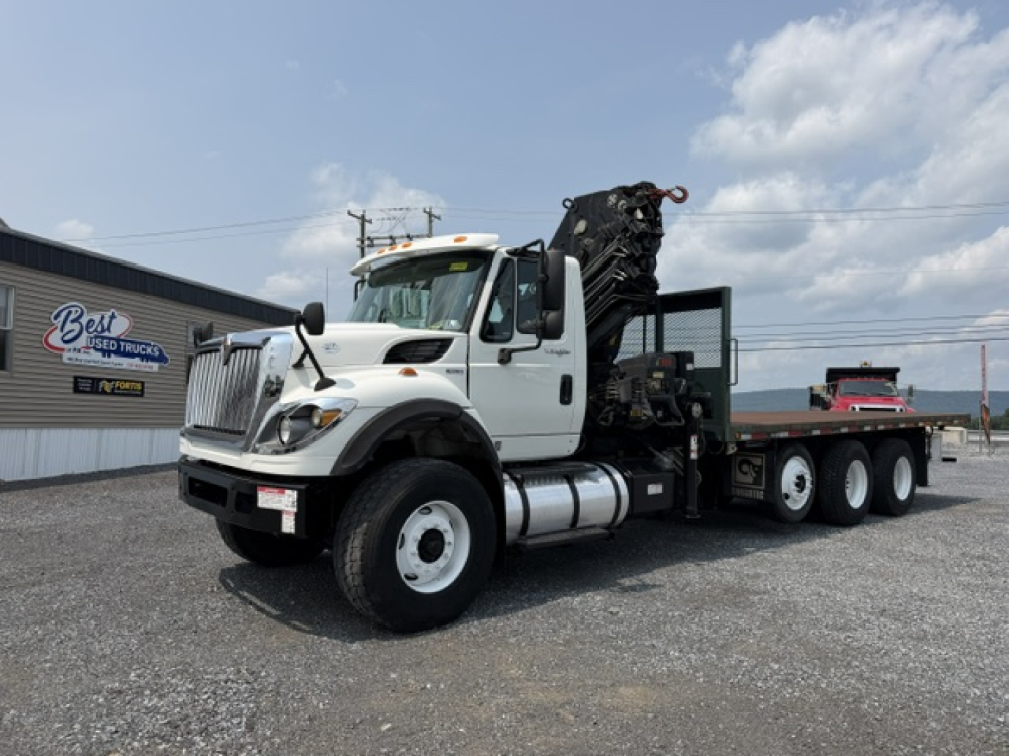 International 7600 SBA Work Star truck with crane, side view showing white cab, flatbed, and hydraulic crane.
