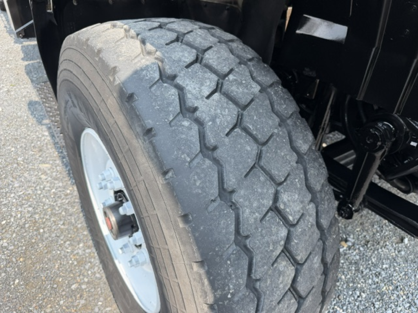 Tire and front suspension of a 2022 International 7600 SBA Work Star truck showing a heavy steer tire and wheel.
