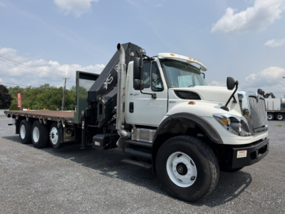 International 7600 SBA Work Star truck with crane on a gravel lot, white cab, flatbed with black crane arm, front grille, and dual rear axles.