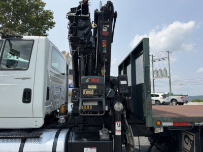 International 7600 SBA Work Star crane truck showing crane arm and control panel with stabilizers and flatbed.