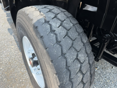 Tire and front suspension of a 2022 International 7600 SBA Work Star truck showing a heavy steer tire and wheel.