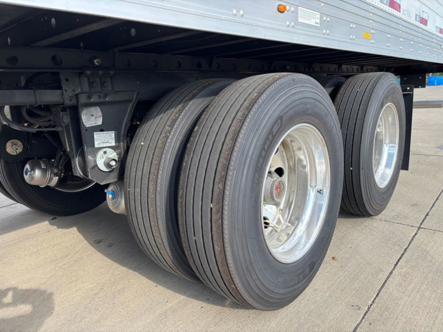 Trailer axle view showing dual rear tires and suspension under a refrigerated utility trailer.