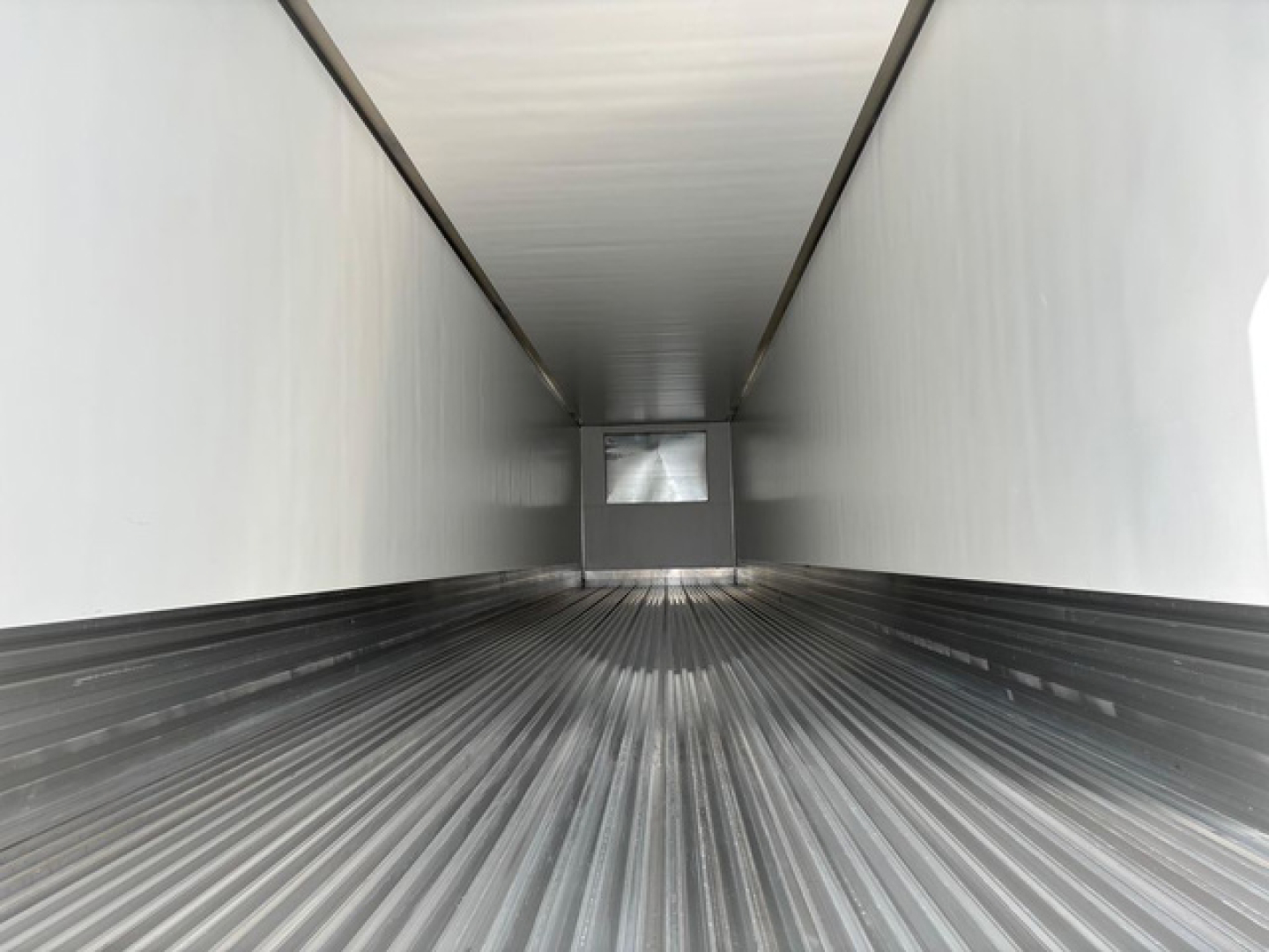 Inside view of a new 2027 Utility Reefer trailer cargo area showing ribbed metal floor and white walls with rear door opening.