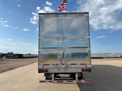 Rear view of a new 2027 utility refrigerated trailer with diamond plate metal doors, rear lights, and a small American flag on top.