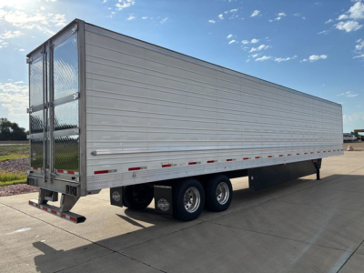 Utility reefer trailer showing side panels, tandem axles, and rear doors with latching hardware.
