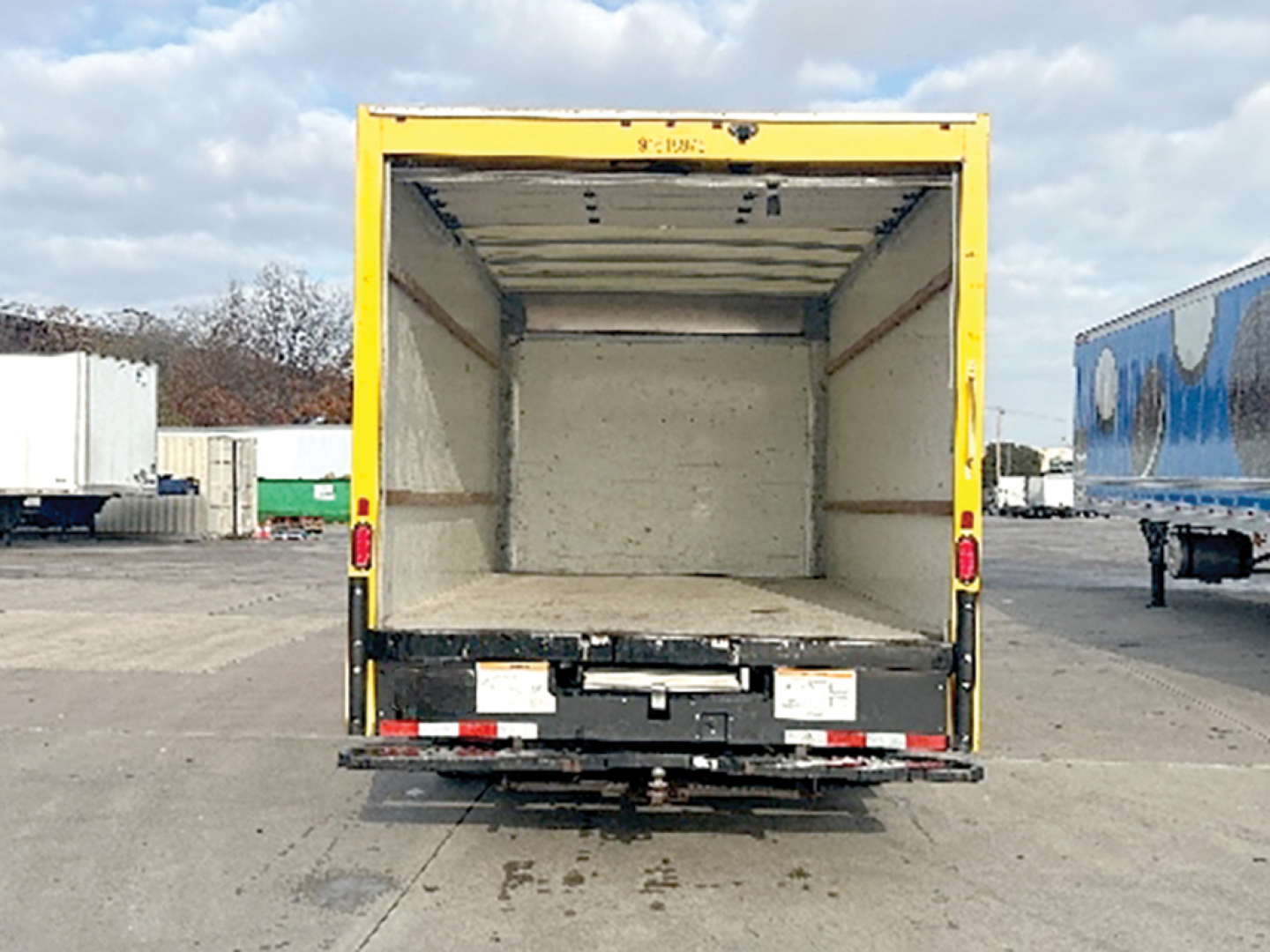 Truck cargo box interior of a 2021 GMC Savana rear view showing empty yellow cargo trailer box with open doors.