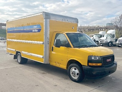 GMC Savana box truck in yellow with cargo box and blue stripe on side, front view showing cab and cargo area