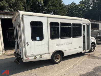 Ford E-350 shuttle bus with wheelchair lift showing side view, rear doors, and windows; visible dents and aging on body.