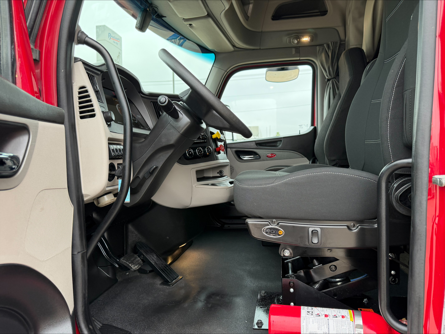Truck cabin interior of a 2023 Peterbilt 579 showing driver's seat, steering wheel, and dashboard area.