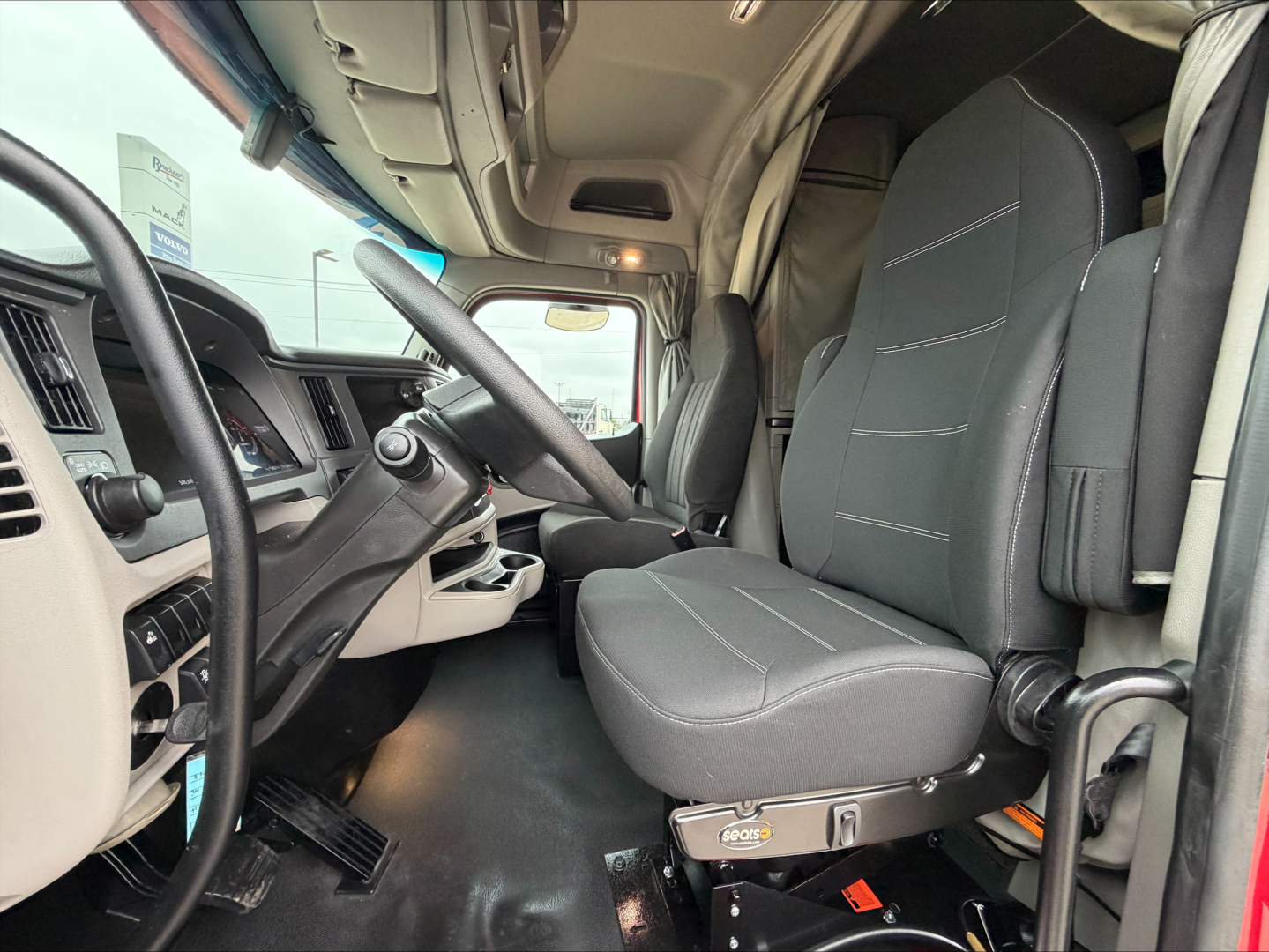 Peterbilt 579 truck cabin interior showing driver seat and dashboard with steering wheel and pedals.