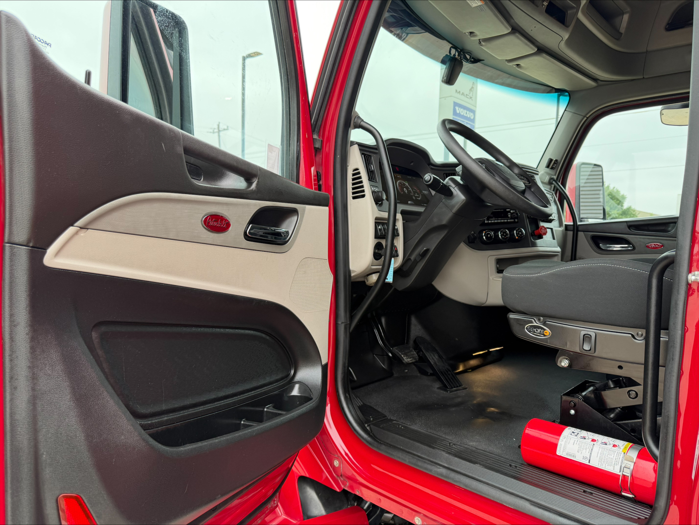 Peterbilt 579 truck interior view with red exterior; driver seat and dashboard visible