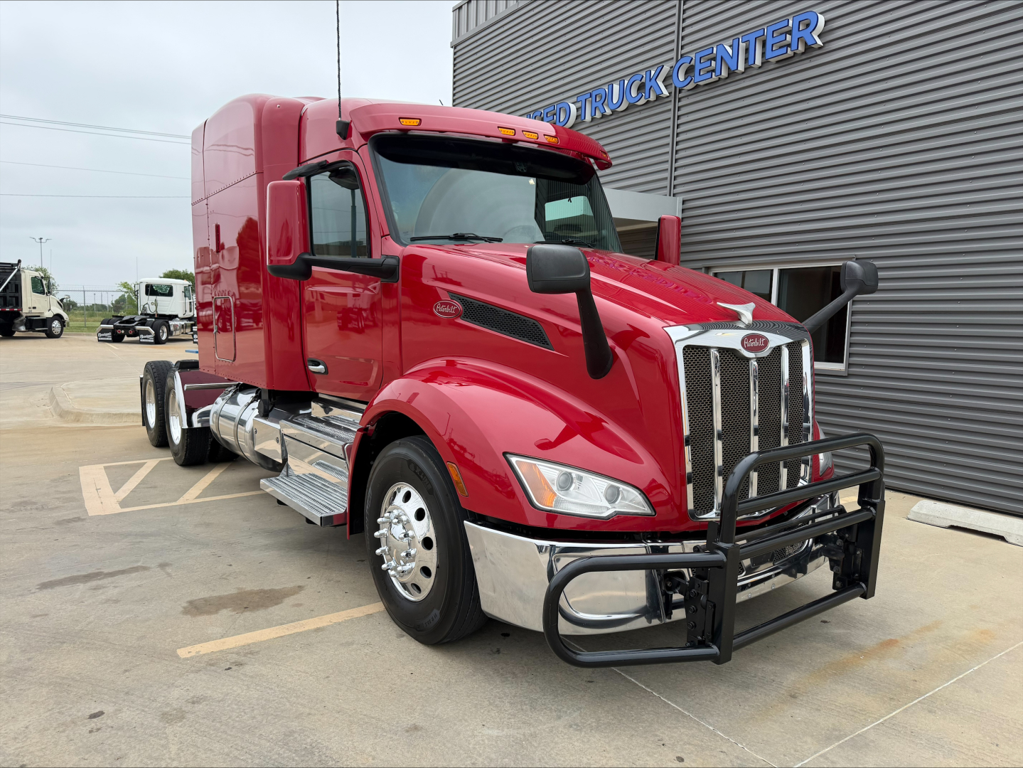 Peterbilt 579 conventional sleeper truck in red, front grille with chrome bumper guard, side mirrors, custom chrome steps, and dual rear axles visible.