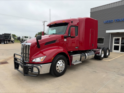 Peterbilt 579 tractor in red, front guard and chrome bumper, daytime at dealership lot.