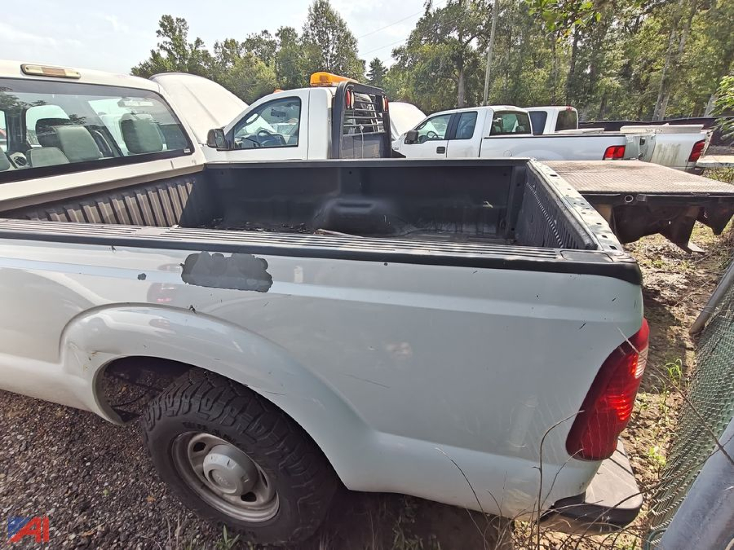Pickup truck bed and rear quarter panel of a 2016 Ford F-250 Super Duty crew cab 2WD in light gray with tail light visible and bed rail scratches.