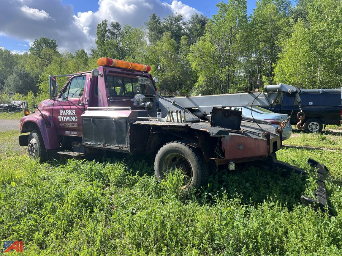 Tow truck body with purple cab and black flatbed in grassy lot, rear equipment, Parks Towing lettering on driver door.
