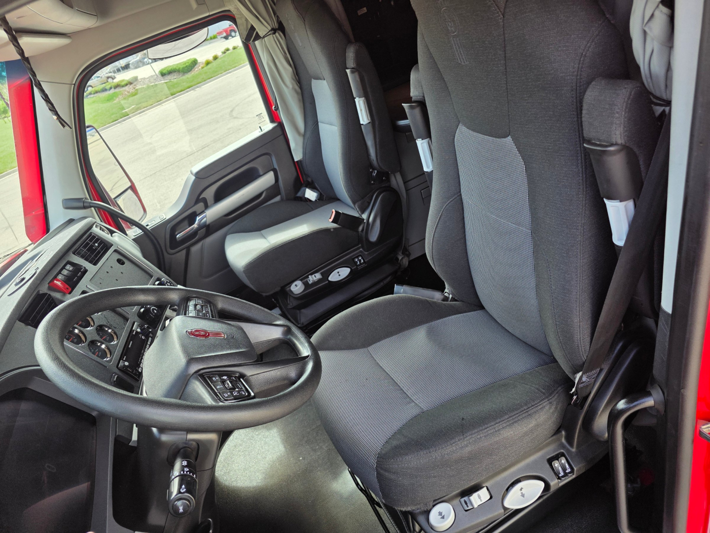 Truck cab interior of Kenworth T680 with steering wheel, driver seat, and dashboard visible.