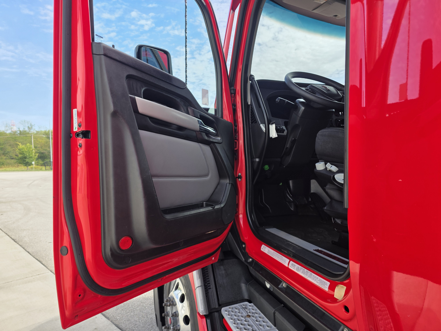 Kenworth T680 truck cab interior with open door showing steering wheel and driver seat.