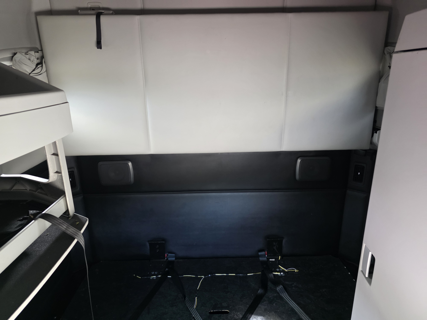 Kenworth T680 sleeper cab interior cargo area with rear window and mounting straps visible.