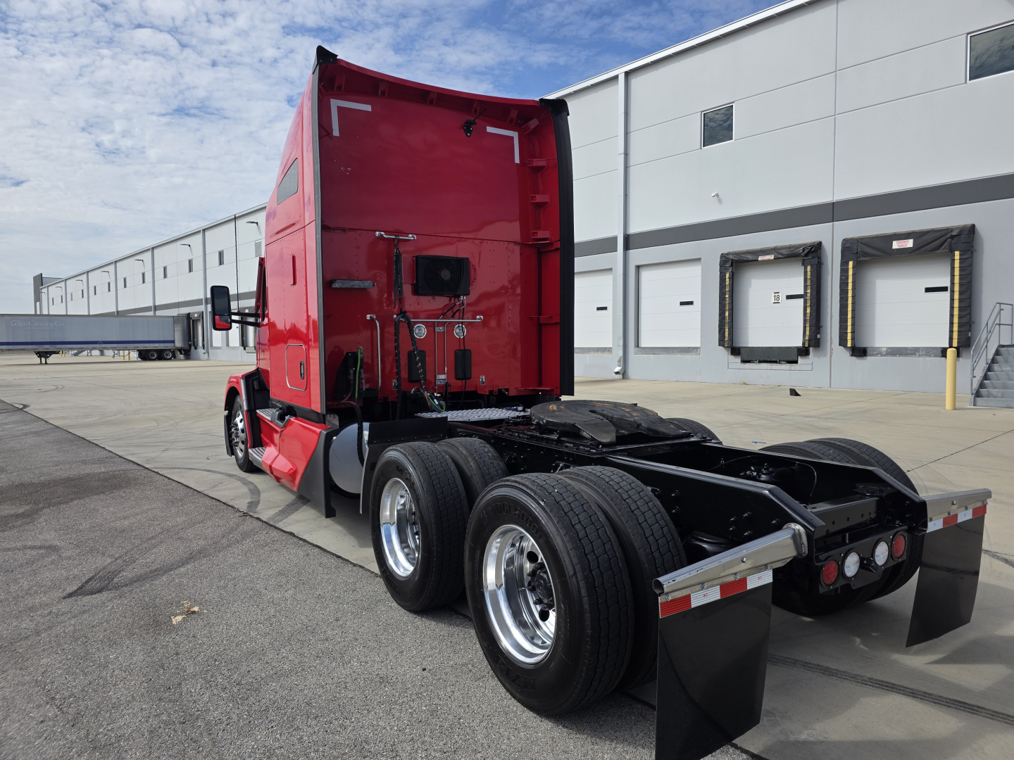 Kenworth T680 tractor cab rear and dual rear axles showing red sleeper cab and attached trailerless chassis.