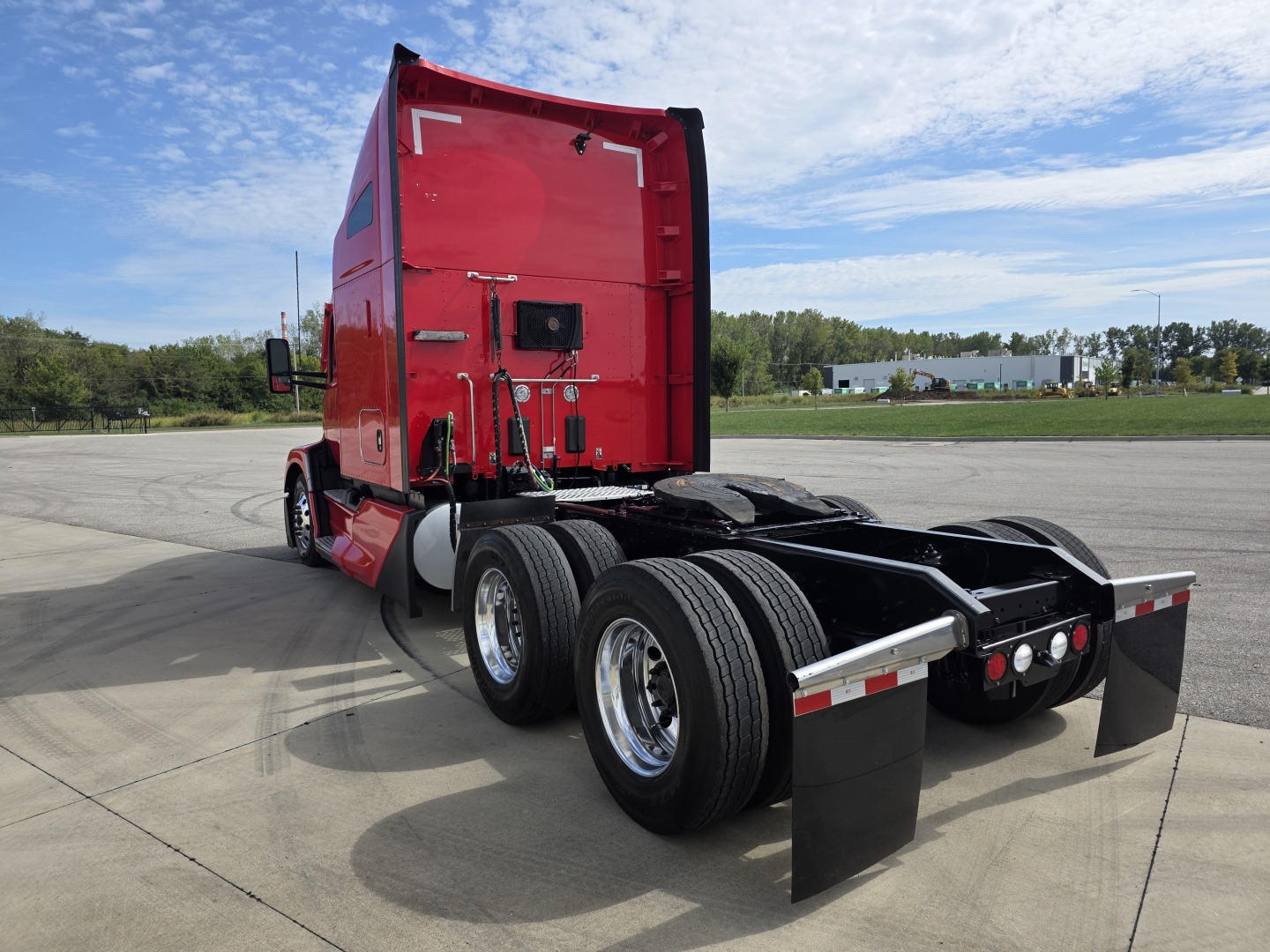 Kenworth T680 truck rear view shows dual rear axles, red sleeper cab, black mud flaps, and fifth-wheel area with chrome wheels.