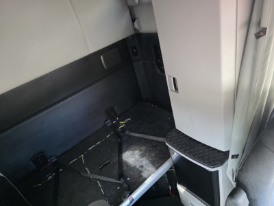 Kenworth T680 cab interior area showing sleeper compartment with seat and seat belt latches, step and storage area near door