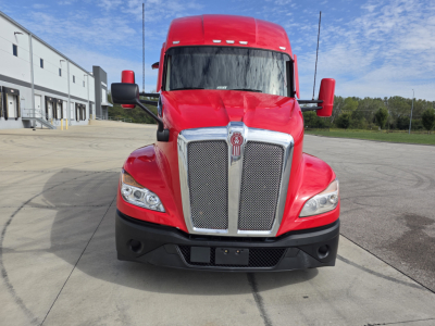 Red Kenworth T680 truck front view showing chrome grille, headlights, and large mirrors.