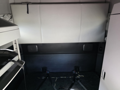 Kenworth T680 sleeper cab interior cargo area with rear window and mounting straps visible.