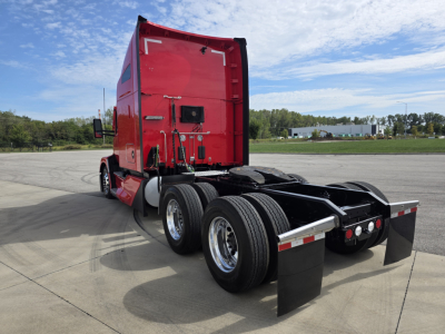 Kenworth T680 truck rear view shows dual rear axles, red sleeper cab, black mud flaps, and fifth-wheel area with chrome wheels.