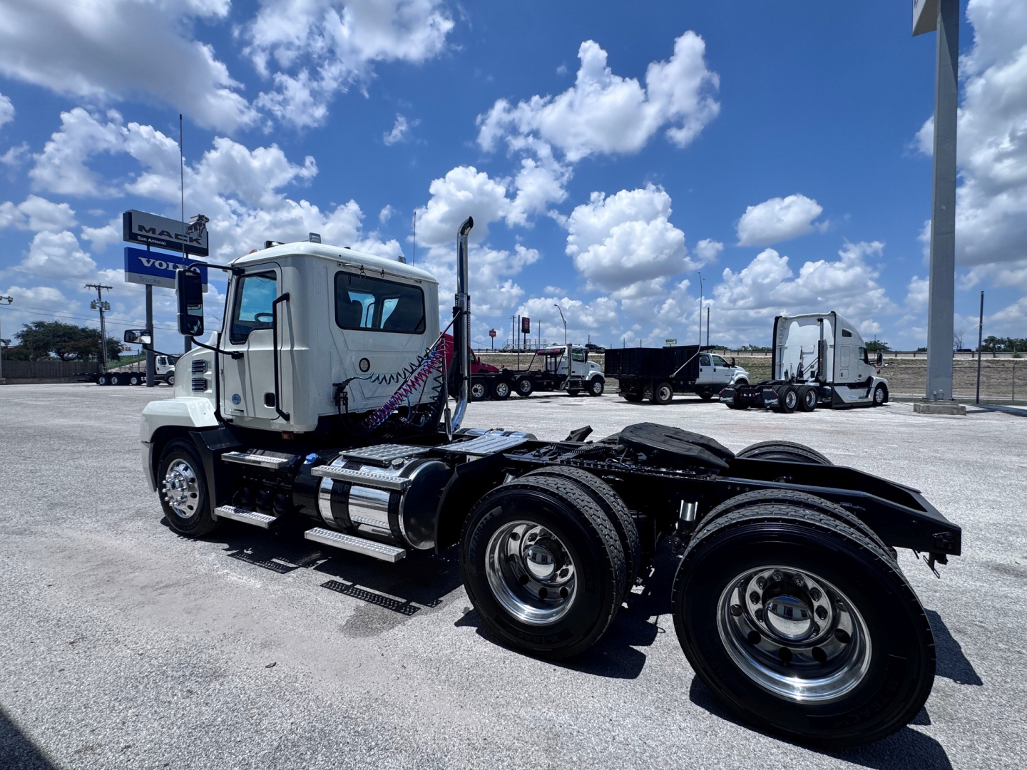 Truck chassis and cab of a 2020 Mack ANTHEM with dual rear axles, fuel tanks, and wheel rims visible in a dealership lot.