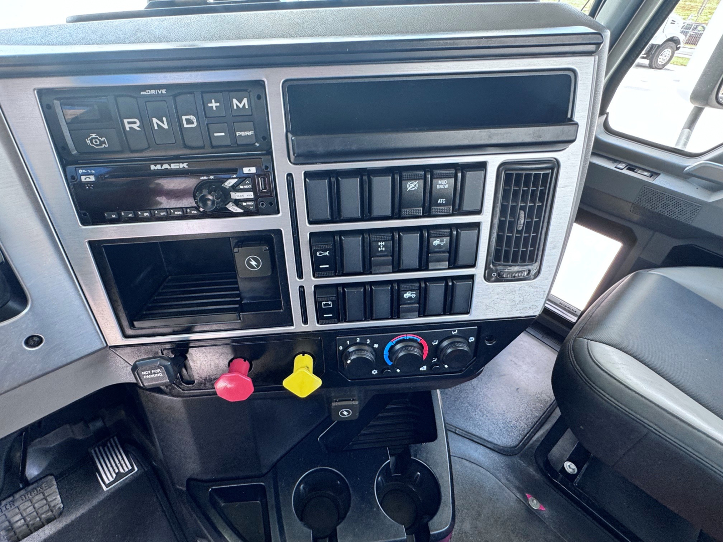 Dashboard panel of a 2020 Mack Anthem truck showing controls, gauges, and a yellow and red knob with climate controls below.