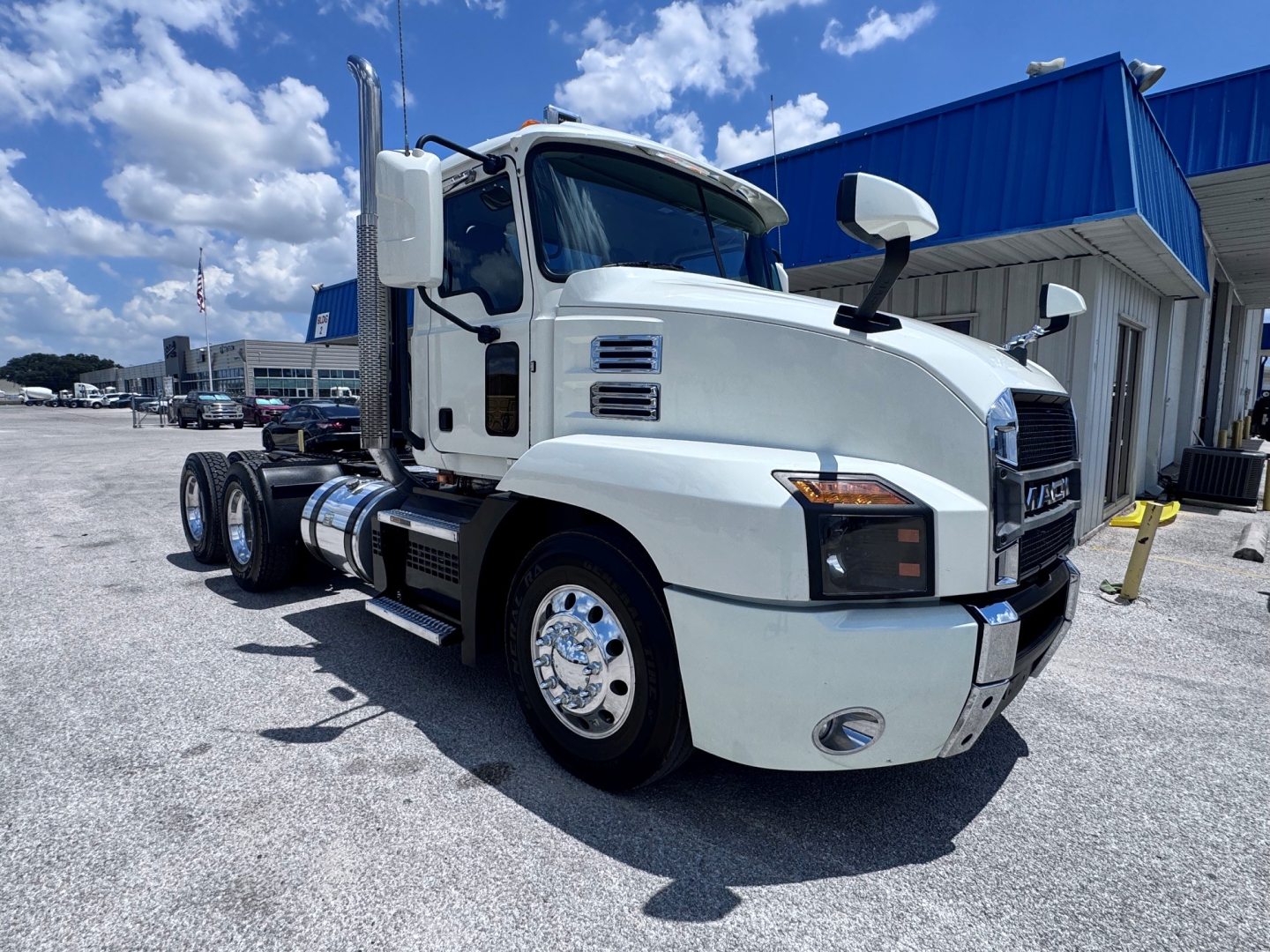 Mack Anthem daycab truck in white, front three-quarter view, with chrome fuel tanks and dual rear axles.