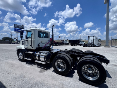 Truck chassis and cab of a 2020 Mack ANTHEM with dual rear axles, fuel tanks, and wheel rims visible in a dealership lot.