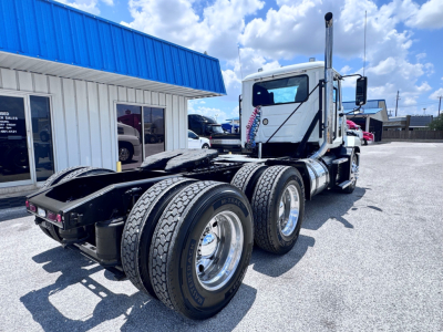 Mack Anthem conventional daycab truck rear view showing dual rear axles and chrome fuel tanks.