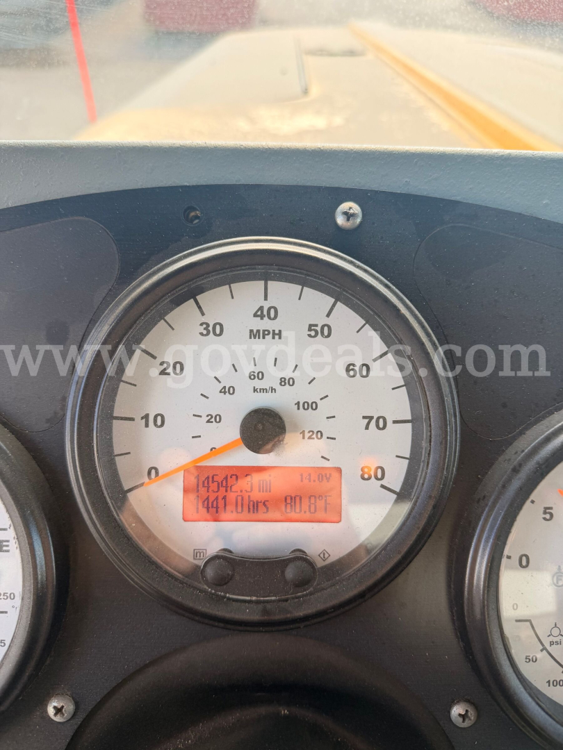 Oshkosh plow truck dash showing speedometer and digital display with mileage and hours, windshield view of road ahead.