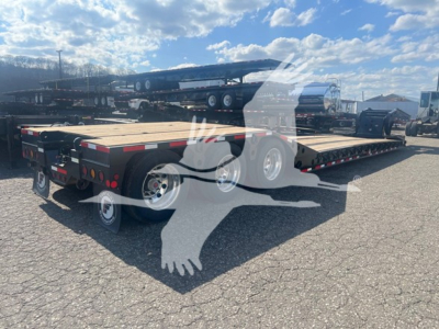 Flatbed trailer on Fontaine paver equipment lot showing dual-axle gooseneck trailer with wooden deck and steel frame.