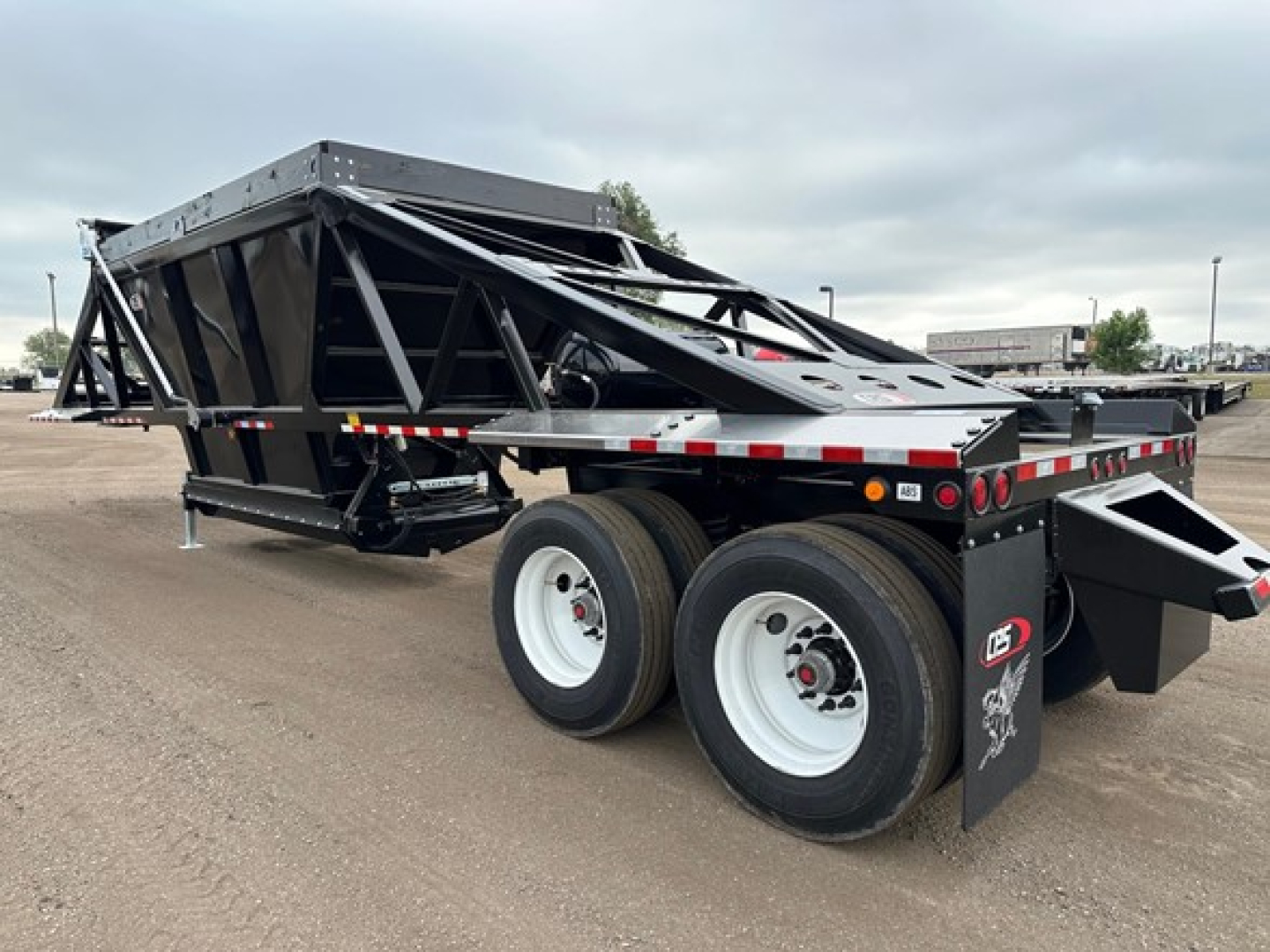 Low-angle view of a new 2027 CPS light weight bottom dump trailer with dual rear axles, open-top steel dump body, black frame, white wheels, and rear dump chute.