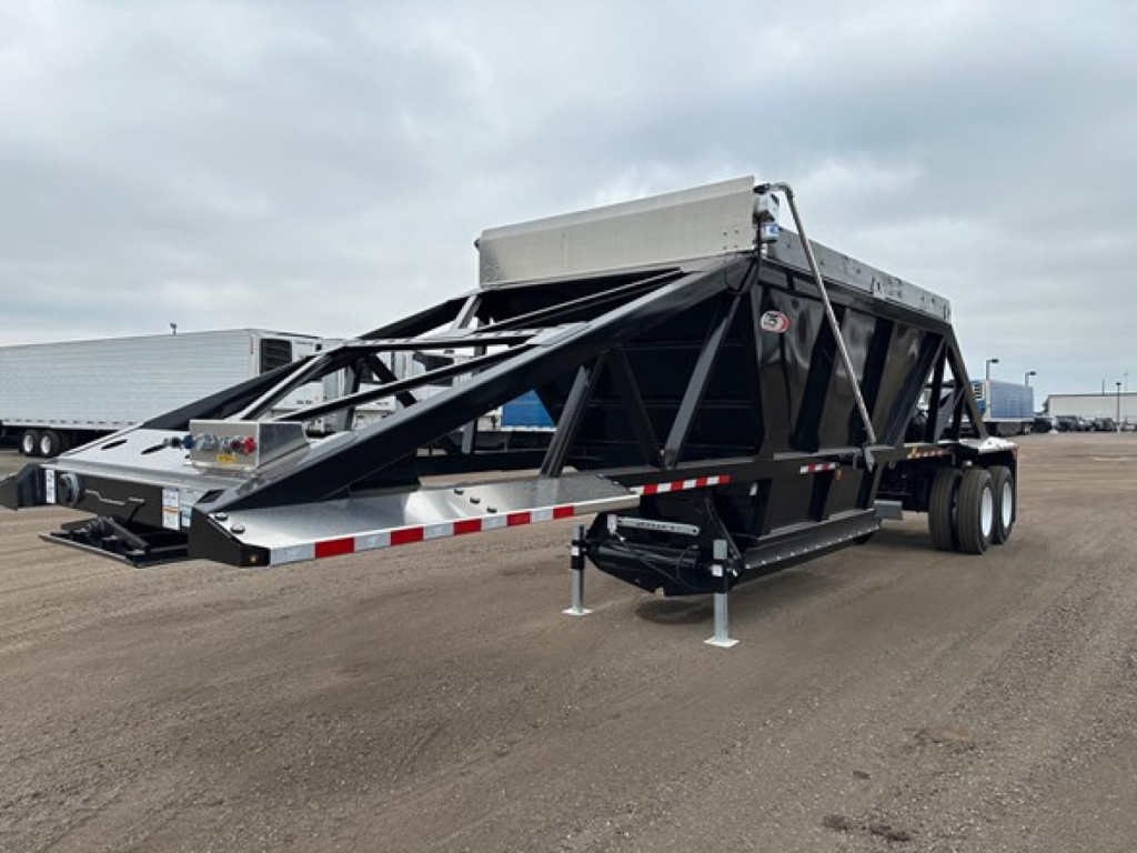 Bottom dump trailer with lightweight, open-frame steel structure and hydraulic dump mechanism, dual axle, ramped tail section, and front storage box.
