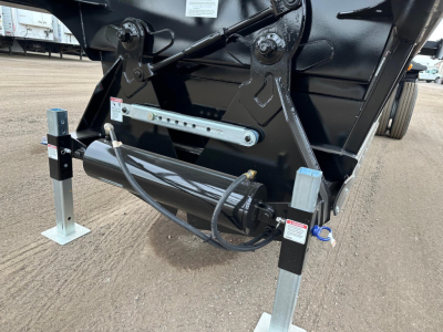 Bottom-dump trailer hitch area showing hydraulic cylinder and support legs with labels and wiring
