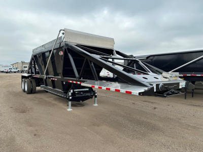 Trailer side view of a black CPS light-weight bottom dump trailer with steel frame and dual tandem axles, showing hopper and hydraulic mechanism.
