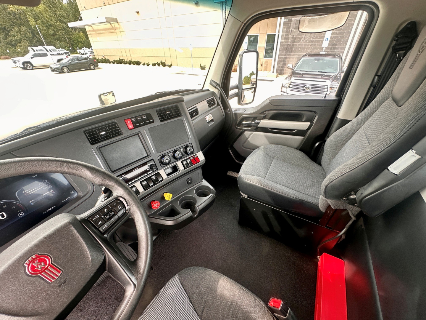 Kenworth T880 cab interior showing dashboard with steering wheel, control panel, and front seats in view.