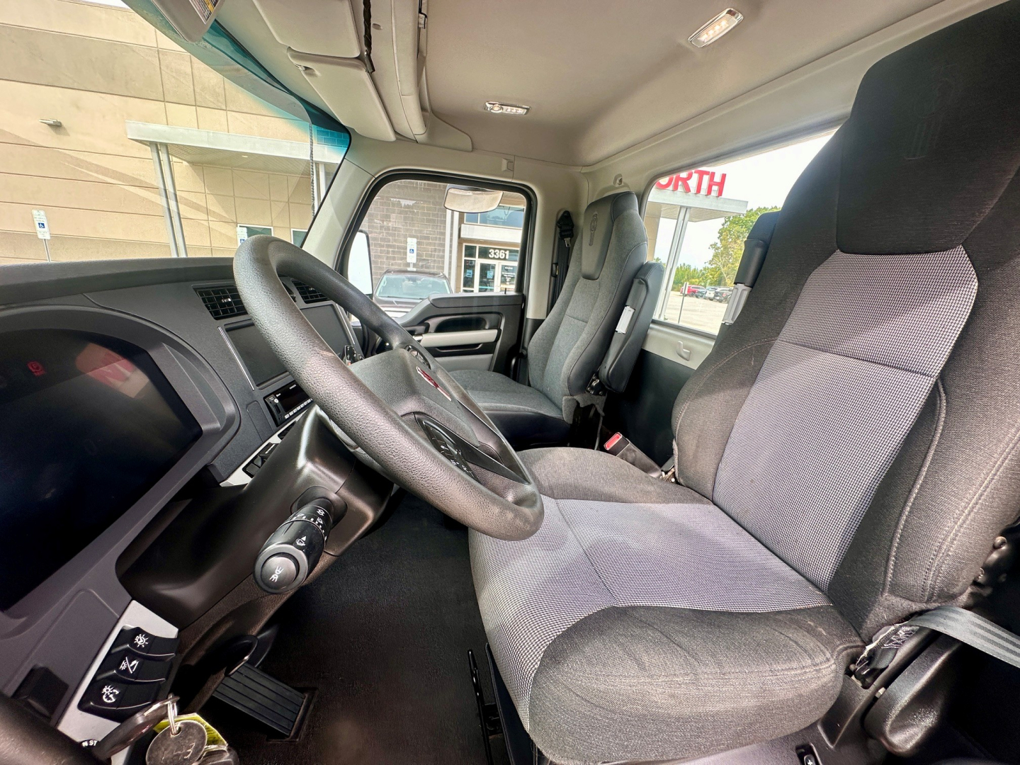 Kenworth T880 truck interior showing steering wheel, driver and passenger seats, dashboard, and windows; view from driver seat.