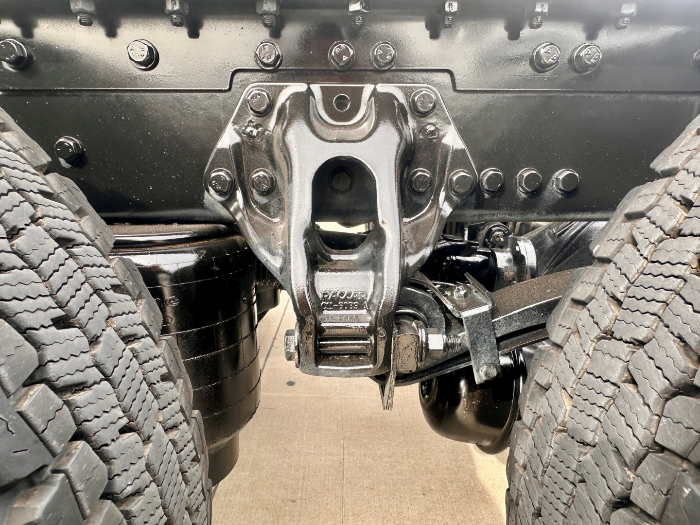 Kenworth T880 rear undercarriage showing fifth wheel, driveshafts, and suspension components between dual rear tires.