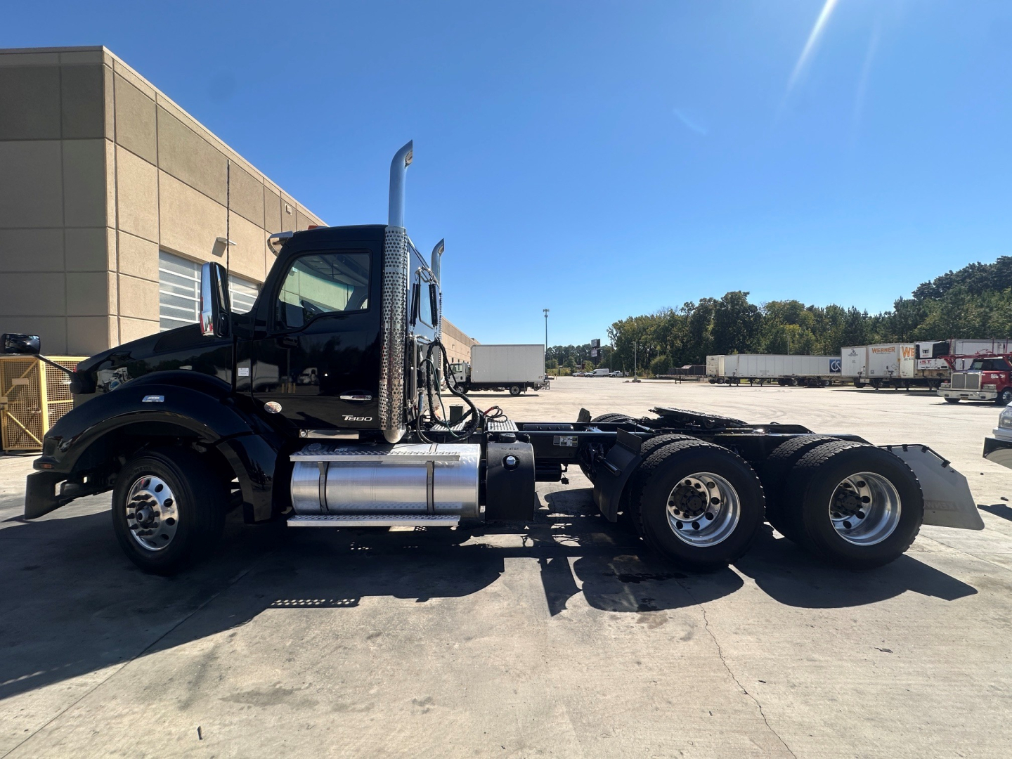Kenworth T880 conventional daycab truck side view showing fuel tanks and dual rear axles.