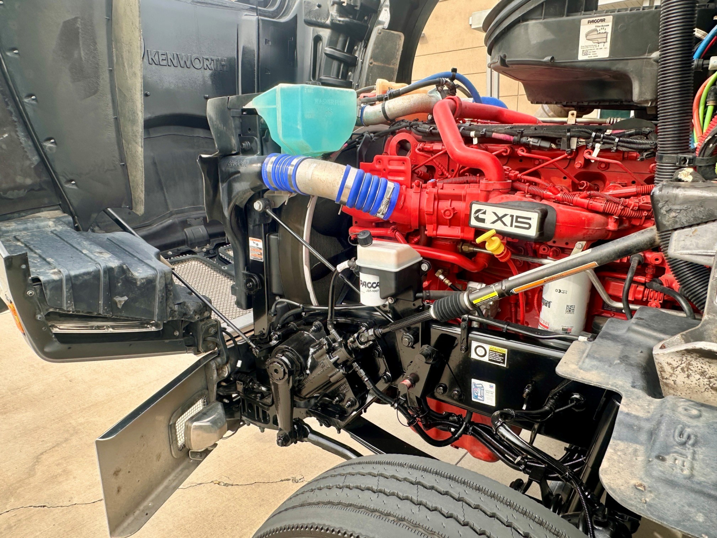 Kenworth T880 engine bay showing red X15 engine and surrounding components.