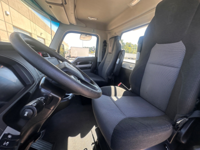 Kenworth T880 truck cabin interior with steering wheel and driver seat visible, gray fabric seats, dashboard, and front windshield.