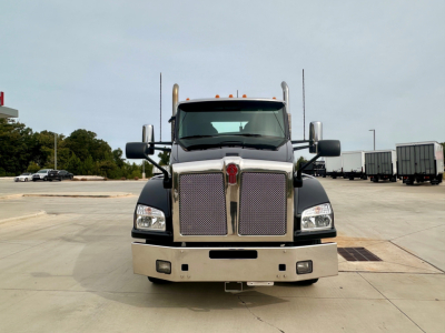 Kenworth T880 conventional daycab truck frontal view showing large grille with vertical chrome bars, black hood, chrome bumper, rectangular headlights, and two hood mirrors.