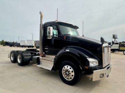 Kenworth T880 tractor in black, front-left view showing chrome grille, tall exhaust stacks, and dual rear axles with aluminum steps and chrome hubcaps.