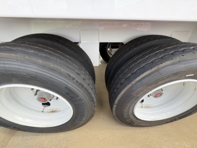 Two rear dual tires of a trailer showing white wheels and black tires with rims.